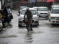 A man rides a bicycle as rains lash Srinagar, Kashmir on July 28, 2022. The weather department has predicted moderate to heavy falls at many...