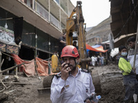 An Iranian firefighter talks on a walkie talkie while standing next to buildings demolished in flash flooding in the flooded village of Imam...