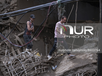 Two Iranian men walk on ruins of a bridge and buildings which are demolished in flash flooding in the flooded village of Imamzadeh Davood in...