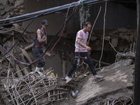 Two Iranian men walk on ruins of a bridge and buildings which are demolished in flash flooding in the flooded village of Imamzadeh Davood in...