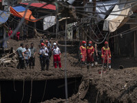 Members of the Iranian Red Crescent Society (IRCC) and firefighters (R) stand on an area which is demolished and covered with mud in flash f...