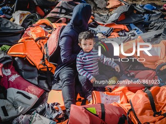 A women takes off her lifejacket in a pile of old lifejackets on the island of Lesbos, Greece, on September 26, 2015. (
