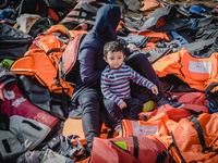 A women takes off her lifejacket in a pile of old lifejackets on the island of Lesbos, Greece, on September 26, 2015. (