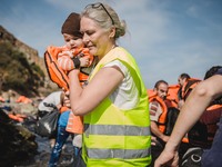 A volunteer carries a child to the shore, in Lesbos, Greece, on September 26, 2015.  (