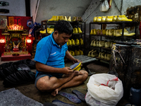 A shoemaker assembles shoes at a home shop. Daily life during heavy rain season in the Mahasin district of East Bangkok, Thailand on August...