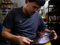 A shoemaker assembles shoes at a home shop. Daily life during heavy rain season in the Mahasin district of East Bangkok, Thailand on August...