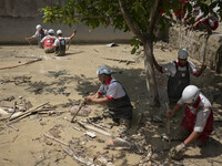 Members of the Iranian Red Crescent Society (IRCC) search for the body of a flood victim at a garden which is filled in floodwaters in the f...