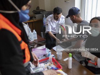 An Iranian volunteer (2nd R) receives medical care from a medical personnel at a mosque in the flooded village of Mazdaran in Firoozkooh cou...