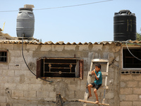 A Palestinian boy eats ice cream during a heat wave and lengthy power cuts in a poor neighborhood of Khan Younis, in the southern Gaza Strip...