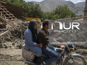 An Afghan refugee family ride motorcycle past a mud-covered destroyed building five days after a sudden flooding in the flooded village of M...