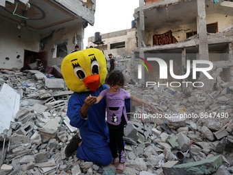 A Palestinian clown plays with a child during a show amidst the rubble of a building destroyed in the latest round of fighting between Israe...