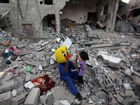 A Palestinian clown plays with a child during a show amidst the rubble of a building destroyed in the latest round of fighting between Israe...