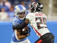Wide receiver Amon-Ra St. Brown (14) of the Detroit Lions carries the ball under the pressure of cornerback Casey Hayward (29) of the Atlant...