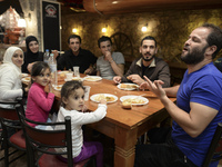 Happy family from Syria having their evening meal together at the Aspa Boomerang Restaurant, as the owner Michael Pastrikos, helped by his f...