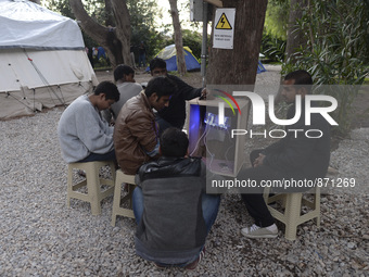 Migrants from Pakistan charge their mobile phones, near the main Police station in Kos Town, as hundreds of new arrived migrants awaiting on...