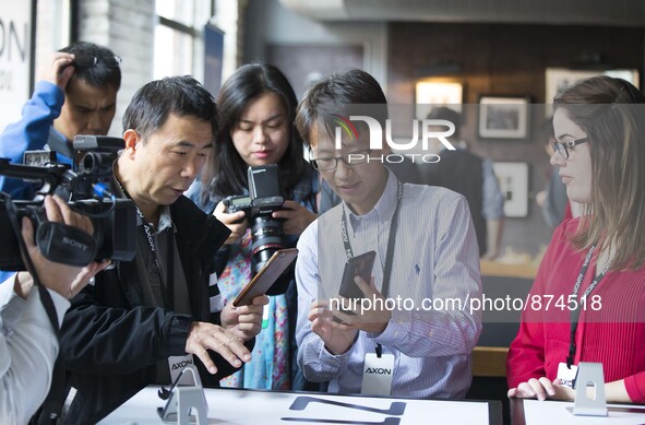 (151027) -- TORONTO, Oct. 27, 2015 () -- Henry Hui (2nd R), project manager of ZTE Canada Inc., introduces an AXON smartphone to visitors du...