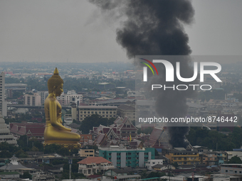 Smoke rises in the air from a community fire near a giant Buddha statue in Bangkok on August 30, 2022 in Bangkok, Thailand. (