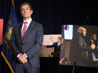Dr.  Mehmet Oz stands next to a picture of John Fetterman on a debate stage, during a press conference with U.S. Senator Pat Toomey, in Phil...