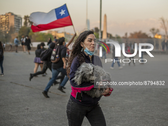 A woman holds her dog as she run away from a police water car in Santiago de Chile, on September 6, 2022. Amid at a protest of college stude...