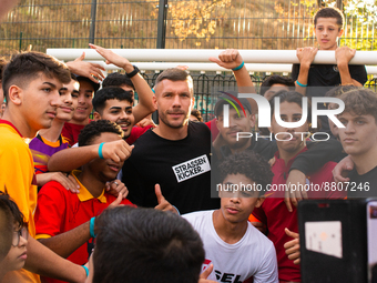 Lukas Podolski, a german football player, takes picture with the youth during his opening of his new soccer training field for youth in Buch...