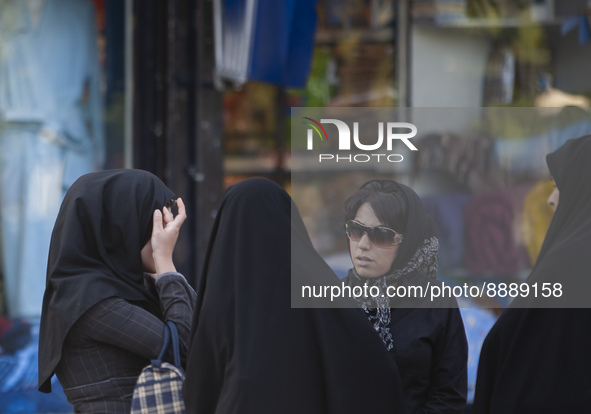 April 23, 2007 file photo shows, An Iranian woman adjusts her scarf as two veiled morality policewomen talk to them in Tehran. Thousands of...