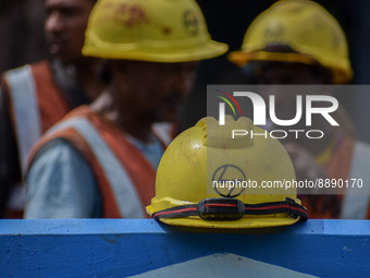 Construction workers walk past a safety helmet of Larsen & Toubro (L&T), at a construction site in Kolkata on September 21, 2022. (