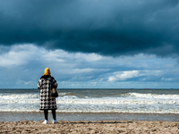 A woman is seen looking to the dark clouds coming, during the celebration of the International Kite Festival held again in the Scheveningen...