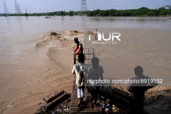 People watch as the Yamuna River gets flooded with water coming from upstream barrages due to heavy rainfall, at Old Iron Bridge in Delhi, I...