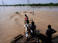 People watch as the Yamuna River gets flooded with water coming from upstream barrages due to heavy rainfall, at Old Iron Bridge in Delhi, I...