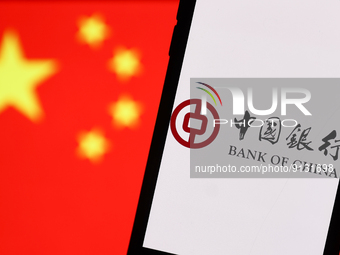 Bank Of China logo displayed on a phone screen and Chinese flag displayed on a screen in the background are seen in this illustration photo...
