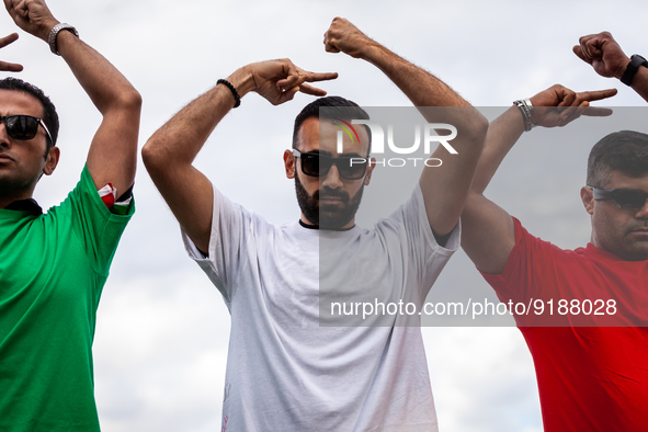 Three men dressed in the colors of Iran's flag pose for photos at a rally and march for Mahsa (Zhina) Amini and those protesting her death i...