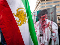 A photo of Iran's supreme leader Ali Khamenei is strkead with handprints and red paint, symbolizing the blood of Iranians killed by the Isla...