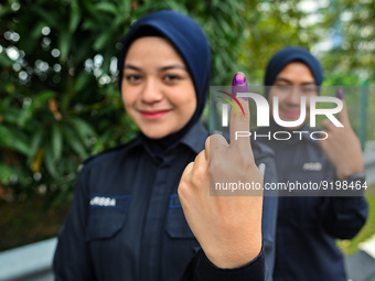 Policewomen show their inked finger after casting their ballot during early voting for the Malaysian general election in Shah Alam, Malaysia...