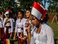 Junior high school students wear Balinese attire and wave Indonesia's flags as they welcome Indonesian President Joko Widodo's convoy drive...