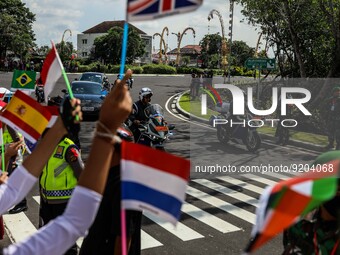 Junior high school students wear Balinese attire and wave flags as they welcome delegates during the G20 summit meeting in Nusa Dua, on the...