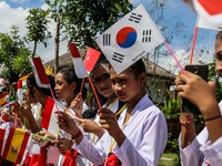 Junior high school students wear Balinese attire and wave Indonesia's flags as they welcome Indonesian President Joko Widodo's convoy drive...