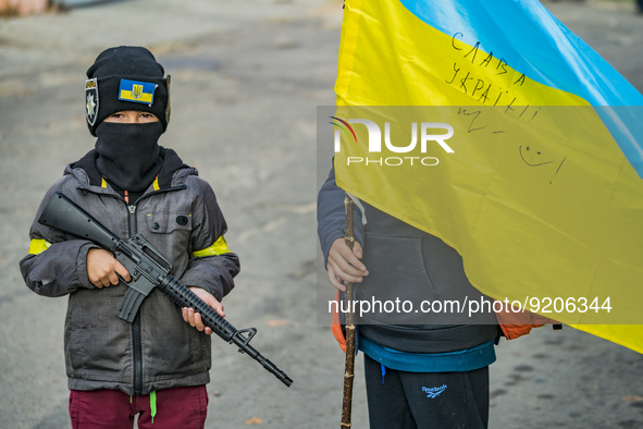 Kids play with a plastic gun and an ukrainian flag in the streets of Kherson city after being liberated by the ukrainian army of the russian...