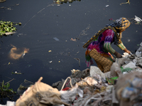 A Women collects used polythene from garbage for recycling besides the River Buriganga in Dhaka, Bangladesh on November 19, 2022. Buriganga...