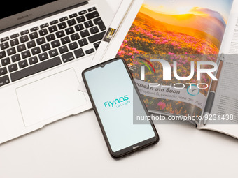 In this photo illustration a Flynas airlines logo seen displayed on a smartphone screen on a desk next to a Macbook and atravel magazine in...