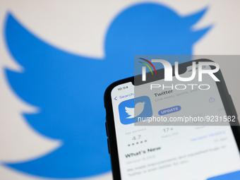 Twitter on App Store displayed on a phone screen and Twitter logo displayed on a screen in the background are seen in this illustration phot...