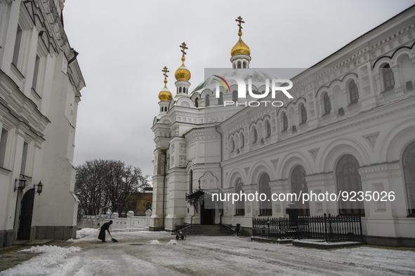 The woman cleanses the snow in the territory of Kyiv Pechersk Lavra, Ukraine, November, 2022 
