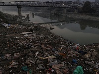 People walk over a bridge as garbage filled banks of River Jehlum is seen in Baramulla Jammu and Kashmir India on 24 November 2022 (