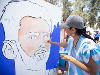 A woman works on a painting depicting Lionel Messi at a Fan Fest before the match between Argentina and Mexico at the World Cup, hosted by Q...