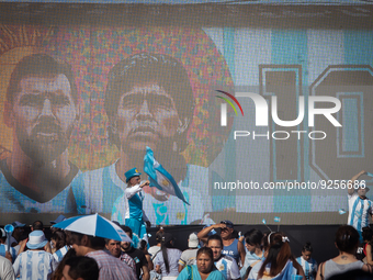 The faces of Lionel Messi and Diego Maradona are seen on a screen as people attend a Fan Fest to watch the match between Argentina and Mexic...