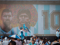 The faces of Lionel Messi and Diego Maradona are seen on a screen as people attend a Fan Fest to watch the match between Argentina and Mexic...