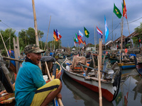 Fishermens are leanding their boat on the wharf with a giant flag in the background, participating countries in the Qatar 2022 world cup in...