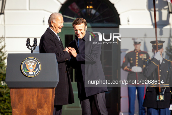 President Joe Biden and President Emmanuel Macron share a laugh while shaking hands during the official arrival ceremony for the French stat...