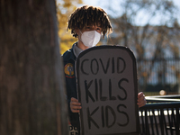 A demonstrator holds a sign reading 'COVID kills kids' outside of the White House in Washington, D.C. on World AIDS Day, December 1, 2022 du...