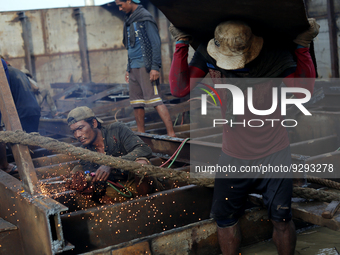 Myanmar workers work at a ship demolition site near Dala jetty in Yangon on December 7, 2022. (