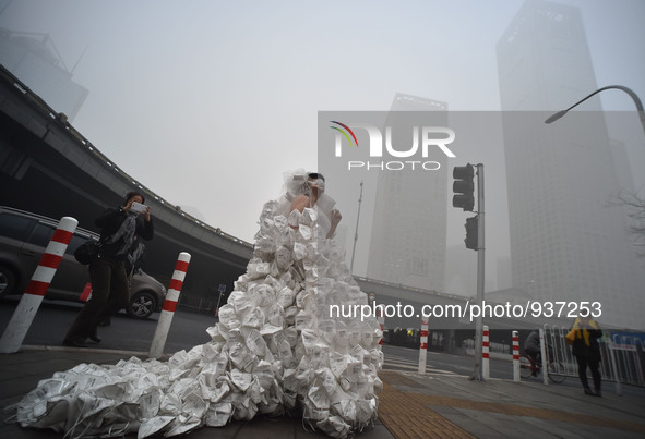 (151201) -- BEIJING, Dec. 1, 2015 () -- Artist Kong Ning wearing a wedding dress made up with 999 respirators walks on the street to call pe...